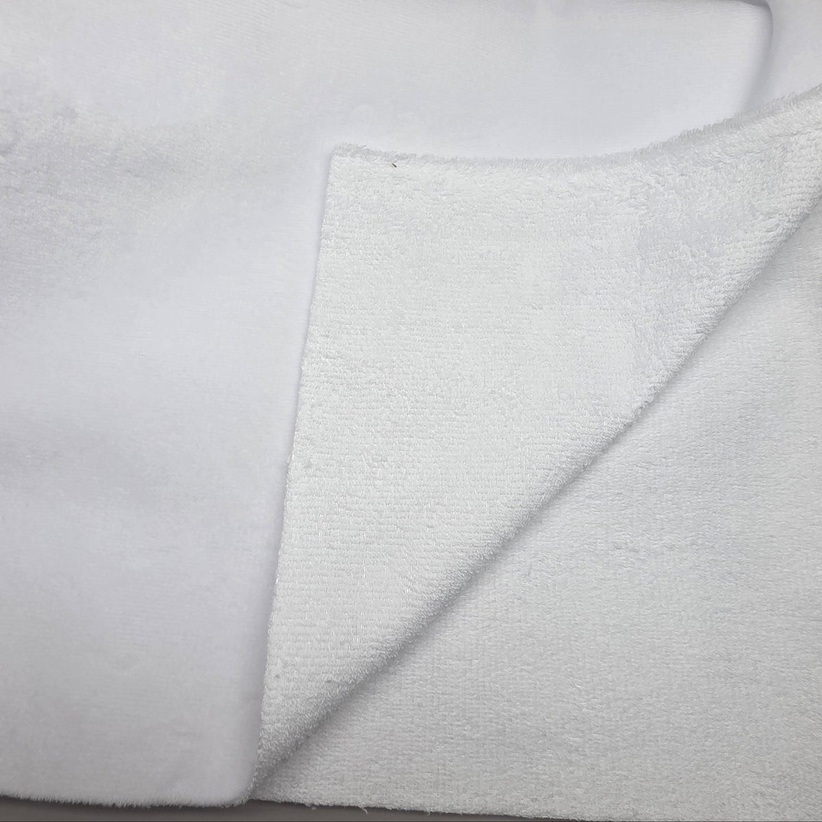 A close-up of a white textured fabric, likely a plush fleece or terry cloth, folded over to show its soft, nubby surface.