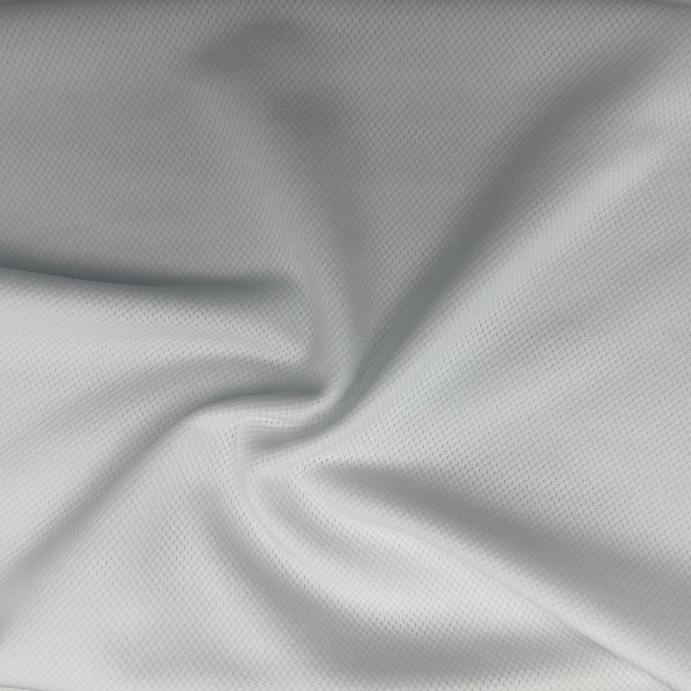 A close-up of light gray athletic fabric with a fine mesh or micro-textured surface, shown with soft folds and shadows.