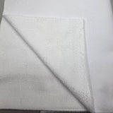A close-up of folded white fabric, showing a soft textured surface and a smooth white layer behind it.